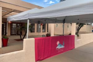 Back of facility courtyard with tent overhang and lit palm trees.