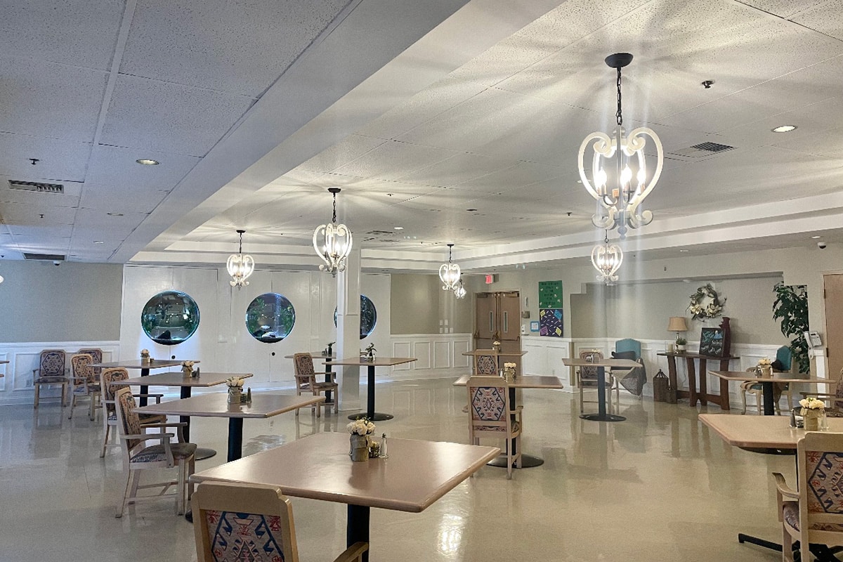 Dining room with chandeliers and flowers and salt and pepper shakers on the tables.