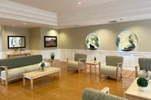 Lobby with shiny hardwood floors and ample chairs and sofa with floral arrangements on coffee tables.